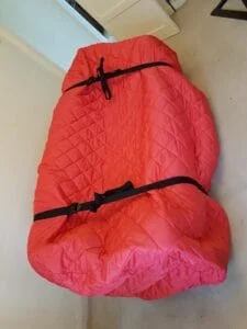 Sofa wrapped in red quilted protective cover secured with straps for moving