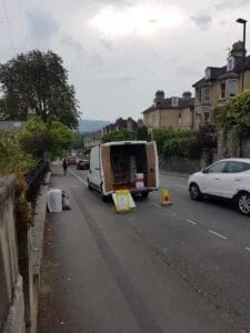 Moving van parked on street with rear doors open and no parking cones set up